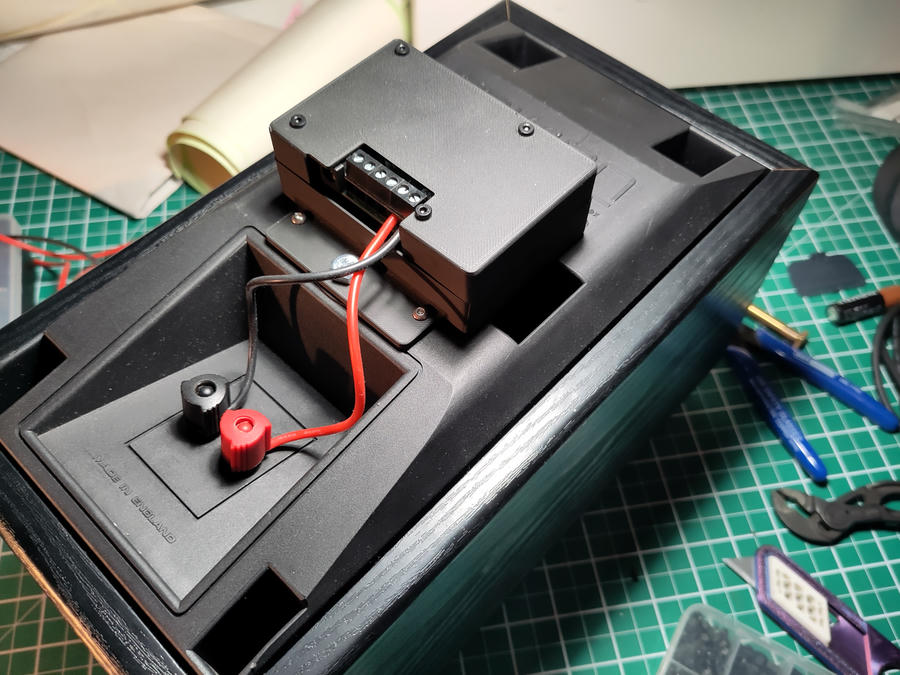 RPi with amplifier hat in a 3D printed case mounted to the back of a speaker sitting on a messy desk.